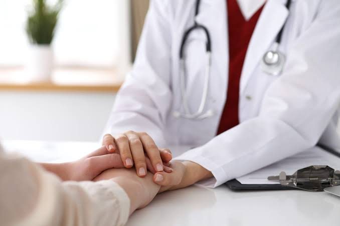 Médica segurando a mão de paciente durante consulta